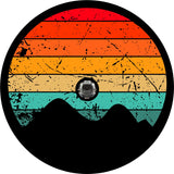 Red, orange, yellow, turquoise rustic stripes fill in the circle of this spare tire cover prototype design with the silhouette of mountains at the bottom and a space to fit a Jeep, Bronco, or other vehicle's spare tire that has a back up camera.