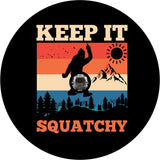 Black vinyl spare tire cover that says Keep It Squatchy, with a bigfoot silhouette giving the middle finger and a colorful mountain backdrop with a camera hole design for back up camera.