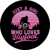 Bigfoot RV tire cover design in pink ombré with sasquatch walking along in the forest and the saying, "Just a girl who loves bigfoot." Also available for Jeep, campers, Bronco, trailer, and more. Design accommodates a back up camera hole 
