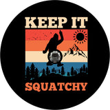 Black vinyl spare tire cover that says Keep It Squatchy, with a bigfoot silhouette giving the middle finger and a colorful mountain backdrop with a camera hole design for back up camera. 