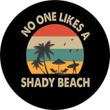 Mock up of a black vinyl spare tire cover with the image of a beach silhouette, surfer, beach chairs and palm trees. Colors of red, turquoise, and orange. The saying no one likes a shady beach